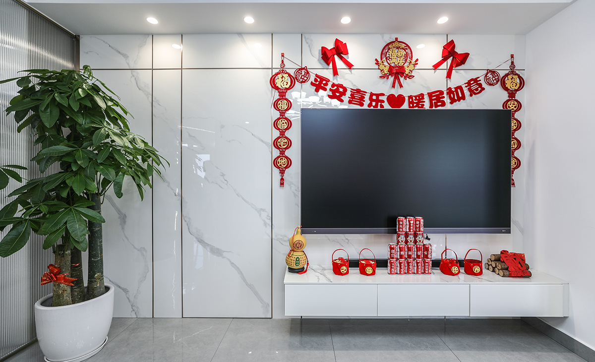 亮光石紋竹木纖維板和極窄線條將房門和背景完美集合，電視柜左邊的裝飾盆景作襯托，巖板臺面電視柜也很大氣，讓空間不但時尚而且清爽。